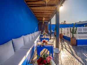 Riad Nuits D'orient Boutique Hotel & SPA في مراكش: غرفة زرقاء مع أرائك وطاولات على شرفة