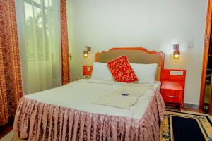 a bedroom with a large bed with red pillows at Home Inn Hotel Rwanda in Ruhengeri