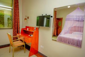 Habitación con escritorio, TV y cama. en Home Inn Hotel Rwanda, en Ruhengeri