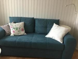 a blue couch with three pillows on it at Ferienwohnung Hirschli in Grub