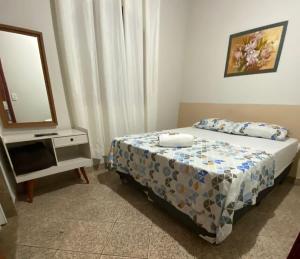 a bedroom with a bed and a dresser with a mirror at Pousada Regina in Cachoeiro de Itapemirim