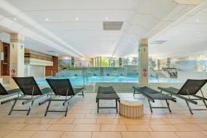 una piscina con sillas y una mesa en un edificio en Ferienappartement Schmetterling, en Sankt Englmar