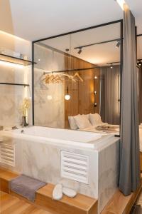 a bathroom with a bath tub and a bed at Mini luxury suites by Sea&theCity in Thessaloniki