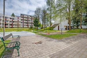 un banco verde del parque sentado en un paseo de ladrillo en Ferienappartement Waldgenuss, en Sankt Englmar