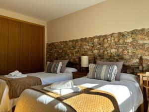 1 Schlafzimmer mit 2 Betten und einer Steinmauer in der Unterkunft Apartamento Mirador del Pantano2 in Vinuesa
