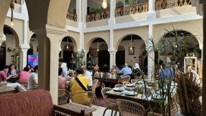 a group of people sitting at tables in a restaurant at Al Koot Heritage Hotel in Al Hofuf