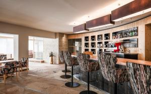 a bar in a restaurant with bar stools at Falkensteiner Hotel & Spa Sonnenparadies in Terento