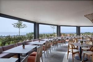 rzędu stołów i krzeseł w restauracji z widokiem na ocean w obiekcie Ammos Luxury Resort w Mastichárionie