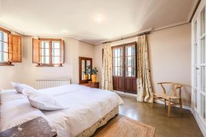 ein Schlafzimmer mit einem großen weißen Bett und einem Stuhl in der Unterkunft Stunning 13th Century Luxury Villa* Garden & Pool in Avila + 66 Fotos