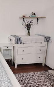 a white dresser with a vase of flowers on it at Csendes pihenés az erdő mellett - Madárfüttyös Vendégház in Pilisszentlászló