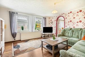 uma sala de estar com um sofá verde e uma televisão em Ferienwohnung zum Specht 