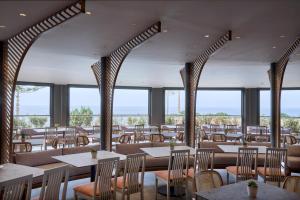 a restaurant with tables and chairs and windows at Ammos Luxury Resort in Mastichari