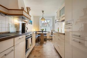 uma cozinha com armários brancos e uma mesa em Ferienwohnung zum Specht 
