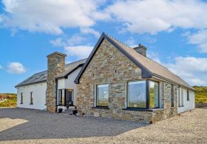 a stone house with large windows on a driveway at Sweet Garden, Mannin - Ballyconneely in Ballyconneely