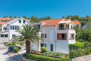 a house with a palm tree in front of it at Apartments Seric in Vrboska