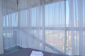 a bedroom with a large window with white curtains at Sea view short stay home in Durban