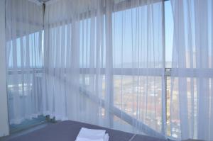 a bedroom with a large window with white curtains at Sea view short stay home in Durban +17 photos