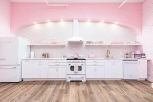 a kitchen with white appliances and pink walls at Kentucky Princess Pretty in Pink in Louisville