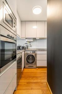 Una cocina con gabinetes blancos y lavadora y secadora. en Breeze Apartment - Matosinhos, en Matosinhos