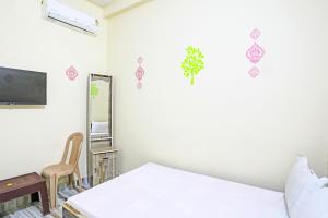 SPOT ON SKP Hotel في Chimur: غرفة نوم بسرير ومرآة وكرسي