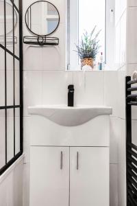 uma casa de banho branca com um lavatório e um espelho em Central London Beautiful 2bed em Londres