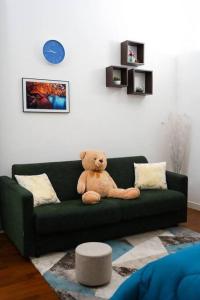 a teddy bear sitting on a green couch at Davids Room Palazzo Tamborino in Lecce