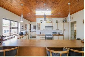 cocina grande con mesa de madera grande y sillas en 17 Villa Leadwood, en Jeffreys Bay