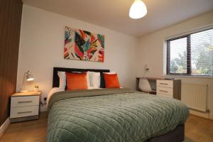 um quarto com uma cama com almofadas laranja e uma secretária em 2 Bedroom GF Home - Private Parking and Garden em Lancaster