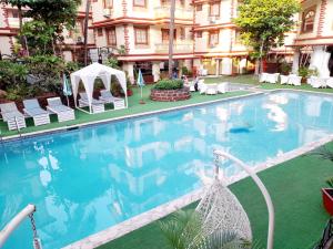 a large swimming pool with chairs and a gazebo at Olive Garden Apartment in Candolim