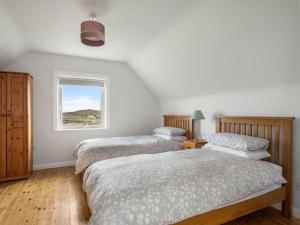 1 dormitorio con 2 camas y ventana en Lake House Mannin, Ballyconneely, en Ballyconneely