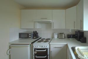 a kitchen with a stove and a microwave at Harbour Inn Appartments in Garlieston