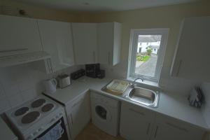 eine weiße Küche mit einem Waschbecken und einem Fenster in der Unterkunft Harbour Inn Appartments in Garlieston