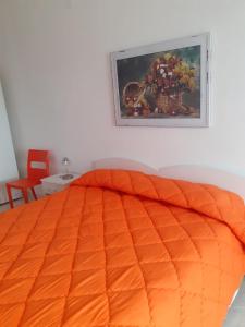 1 dormitorio con 1 cama de color naranja y una pintura en la pared en B&B Villa Rosina, en Satriano di Lucania