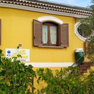 una casa amarilla con una ventana y un cartel en B&B Villa Rosina, en Satriano di Lucania