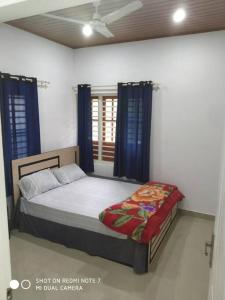 a bedroom with a bed with blue curtains and a window at 2bhk Villa Vythiri, Kunnathidavaka, kerala in Vayittiri +14 photos