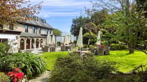 un jardín con mesas y sombrillas frente a un edificio en Le Friquet Hotel en Castel