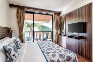 a bedroom with a bed with a television and a balcony at Riva Boutique Apartments in Porvorim