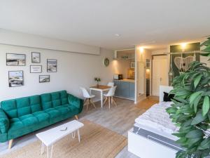 ein Wohnzimmer mit einem grünen Sofa und einer Küche in der Unterkunft FeWo C 1-2 "Kleine Auszeit" in Sierksdorf