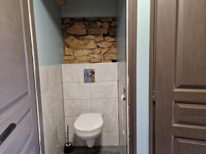 un piccolo bagno con servizi igienici e un muro in pietra di Roulotte La Maison Des Trois Grands a Sannat