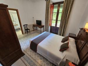 1 dormitorio con cama, escritorio y ventana en Hotel España, en Lanjarón