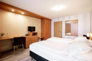 a bedroom with a bed and a desk and a television at Hotel zum Buchenberg in Saint-Vith