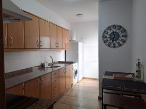 a kitchen with wooden cabinets and a clock on the wall at Vv Salitre in La Santa
