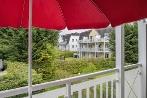 オストゼーバート・ニーンハーゲンにあるFerienwohnung Strandnäheの家のバルコニーにある赤い傘