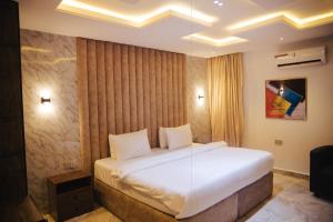 een slaapkamer met een groot wit bed in een kamer bij DE LEVERAGE HOTEL & SUITES in Lagos
