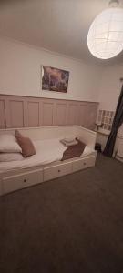 a large white bed in a room with a ceiling at 3 Bed Home in Heart of Cardiff in Cardiff