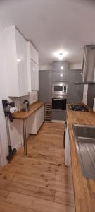 a kitchen with white cabinets and a wooden floor at 3 Bed Home in Heart of Cardiff in Cardiff