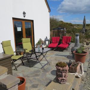 a patio with yellow and red chairs and a table at Mizen View in Goleen