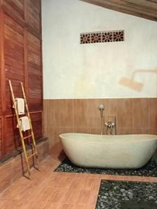 a bath tub in a bathroom with wooden walls at Loka Amertha in Sidemen