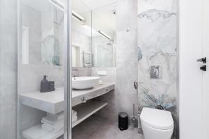 a white bathroom with a sink and a toilet at Studio with a balcony and AC - Rajska 3 street in Kraków