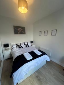 a bedroom with a large bed with black and white sheets at Class Apartments in Peterhead